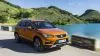 ista de un Seat Ateca naranja circulando por una carretera cerca de un lago