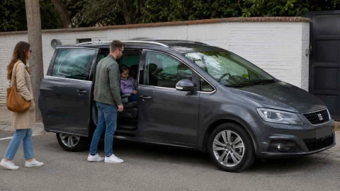 Familia junto a un coche de 7 plazas amplio y moderno preparado para viajes familiares y desplazamientos cómodos