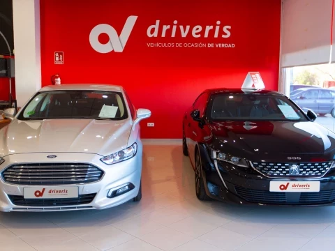 Coches en exposición en Driveris La Esperanza en Huelva con fondo rojo.