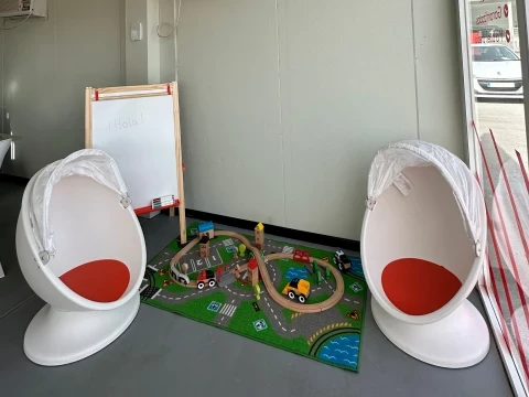 Zona infantil en el concesionario Driveris con alfombra de juegos y sillas colgantes