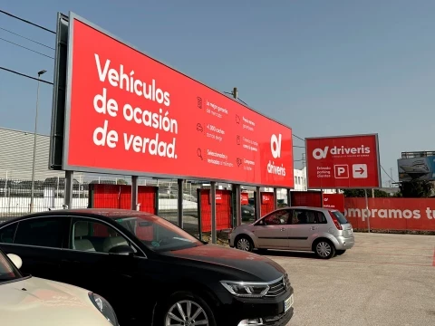 "Vista lateral del concesionario Driveris con coches estacionados y mensaje promocional".