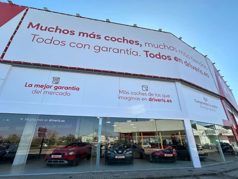 Fachada lateral de Driveris Córdoba con mensajes promocionales sobre coches de ocasión.