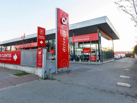Vista lateral del concesionario Driveris en Sevilla con entrada principal y carteles promocionales