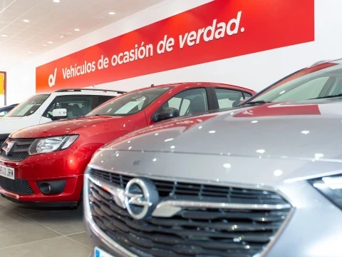 Vista lateral de coches en exposición en Driveris Trigueros con un letrero promocional.