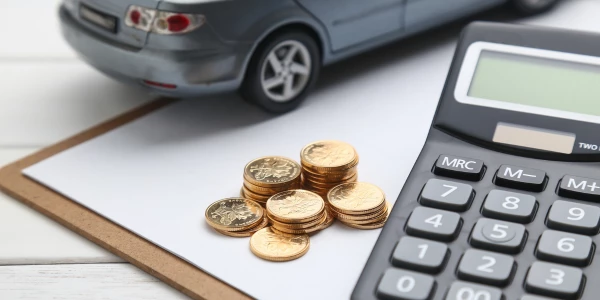 Calculadora, monedas y un coche de juguete en una mesa