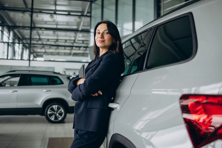 Mujer de negocios apoyada en su coche de empresa