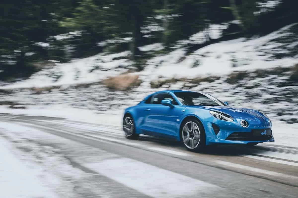 Alpine A110 en carretera nevada mostrando su rendimiento en curvas