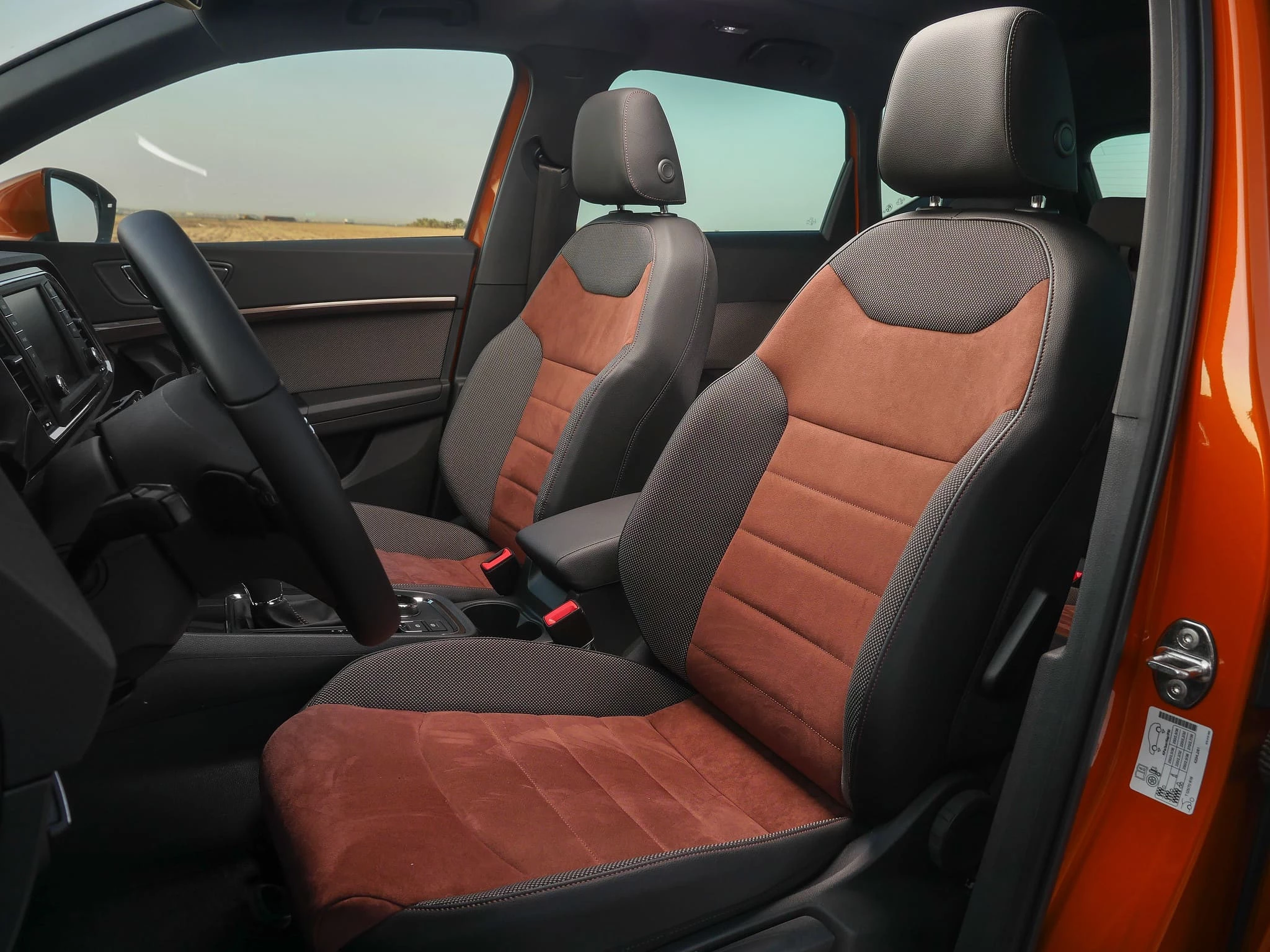 Vista de los asientos delanteros de un Seat Ateca naranja, con tapicería en tela y cuero