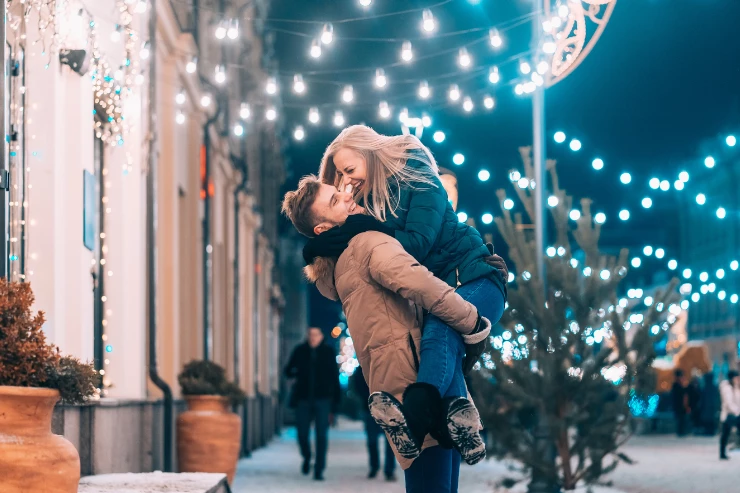 Pareja feliz bajo las luces navideñas