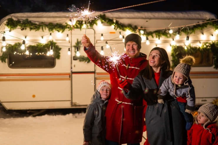 Familia delante de su caravana decorada con luces navideñas