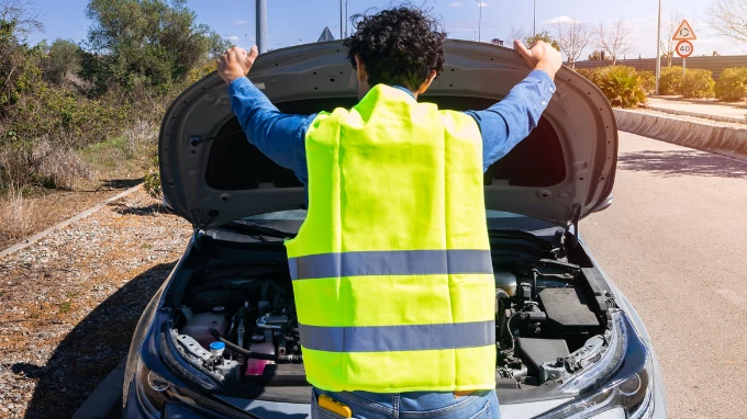 Hombre con su chaleco mirando el motor de su coche