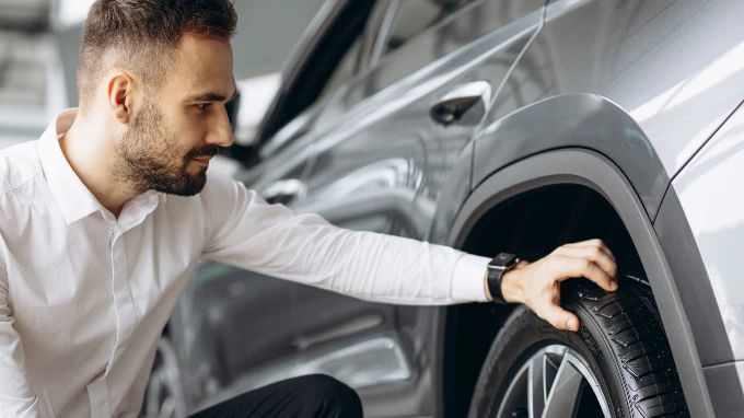 hombre revisando la rueda de su coche de segunda mano