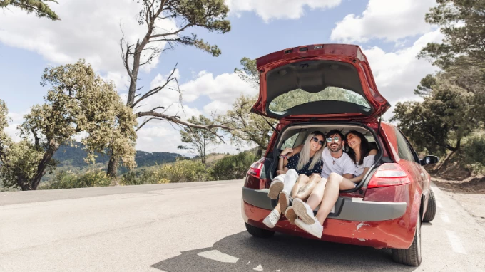 Amigos de viaje dentro del maletero de un coche rojo
